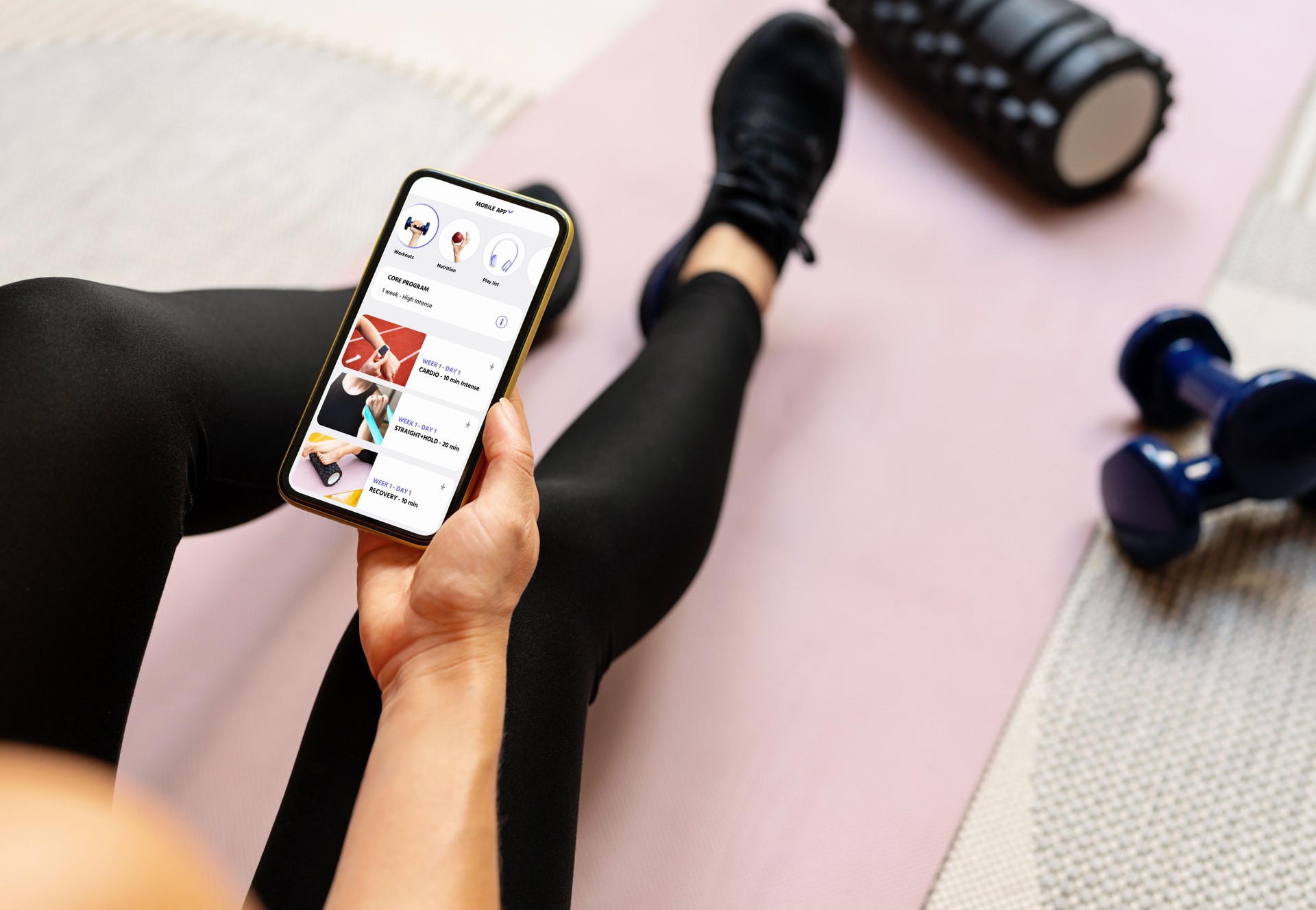 Female sports person sits on yoga mat and holding smart phone with white empty screen in her hand. Mobile phone and fitness. Workout mobile app.