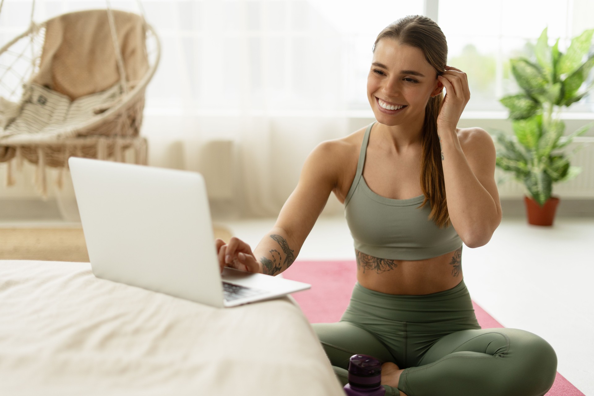 Smiling sportswoman using laptop for online workout at home
